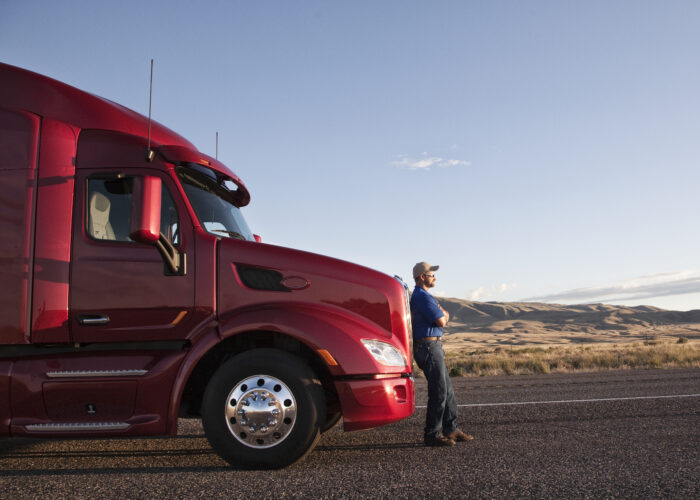 Truck driver leaning on the grill of his commercial truck. Truck driver leaning on the grill of his commercial truck.